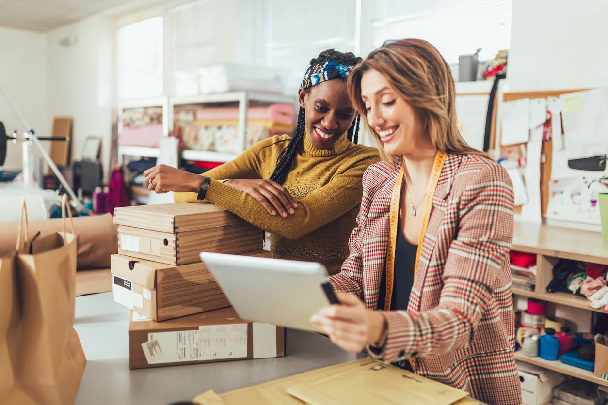 Two women looking at a tablet working on marketing